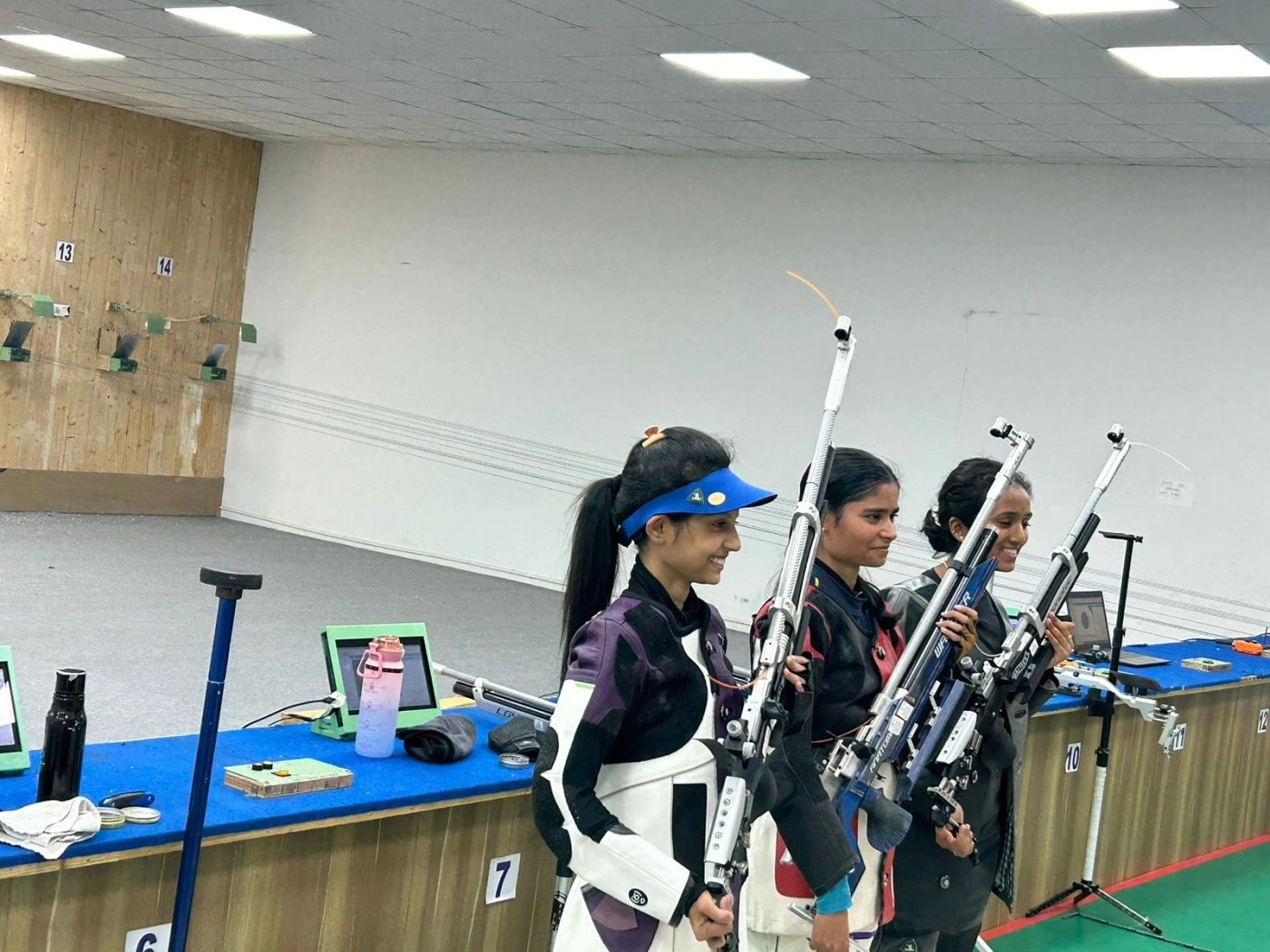 Three medalist athletes holding their air rifles at a competition